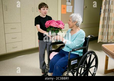 Austin Texas USA, febbraio 11 2014: Nipote di otto anni fa da fiori alla nonna mentre la visita in ospedale. ©Marjorie Kamys Cotera/Daemmrich Photography Foto Stock