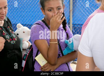 McAllen, Texas USA, giugno 24 2014: Giovane donna in fila in attesa di salire a bordo di una navetta che porterà lei e sua madre alla stazione degli autobus di McAllen, Texas dal rifugio della Carità Cattolica, dove ha ricevuto abiti puliti, una doccia e cibo. È stata catturata dagli agenti della polizia di frontiera degli Stati Uniti mentre ha attraversato il confine in Texas dal Messico. ©Marjorie Kamys Cotera/Daemmrich Photography Foto Stock