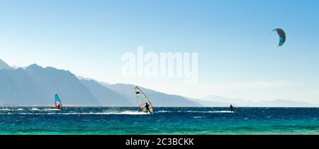 Surfisti e kitesurfisti ride in Mar Rosso sullo sfondo della costa rocciosa in Egitto Dahab Foto Stock