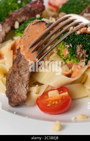 Tagliatelli con fette di bistecca su una piastra Foto Stock