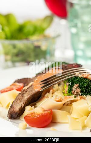 Tagliatelli con fette di bistecca su una piastra Foto Stock