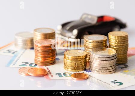 Pila di monete in euro su banconote in euro e auto classica per sfondi. Germania Foto Stock