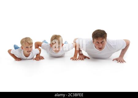 Padre con due figli. Il giovane uomo con bambini isolati su sfondo bianco sta facendo esercizi ginnici. Push-up. Genitorialità, concetto di l sano Foto Stock