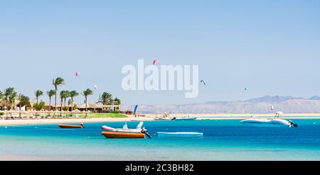 Hotel con palme sul Mar Rosso in Egitto Dahab con barche e kite surfisti Foto Stock