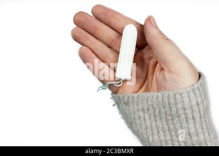 Tampone bianco pulito sulla mano della donna isolato su sfondo bianco. Tempo mestruazione. Igiene e protezione. Primo piano Foto Stock