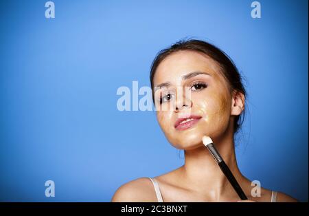 Donna allegra che applica la maschera dorata Foto Stock