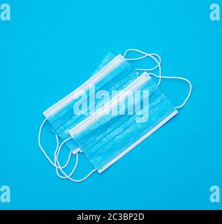 Blue medici sterili maschera bianca con fasce elastiche per medici su un fondo azzurro, laici piatta Foto Stock