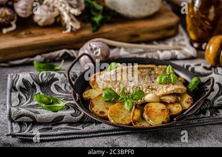 Delizioso pesce con patate arrosto e bio aglio Foto Stock