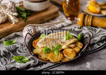 Delizioso pesce con patate arrosto e bio aglio Foto Stock