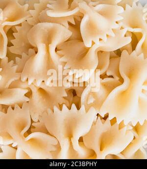 Primo piano di fondo di pasta di farfalle. Le farfalle sono un tipo di pasta/noodle comunemente noto come pasta con cravatta o pasta con farfalla. Foto Stock