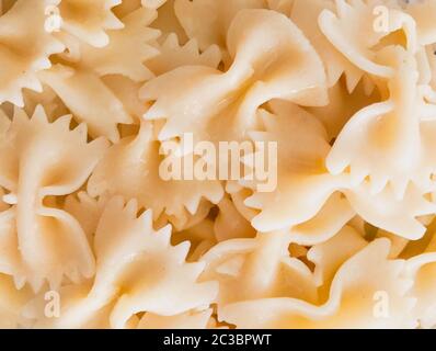 Primo piano di fondo di pasta di farfalle. Le farfalle sono un tipo di pasta/noodle comunemente noto come pasta con cravatta o pasta con farfalla. Foto Stock