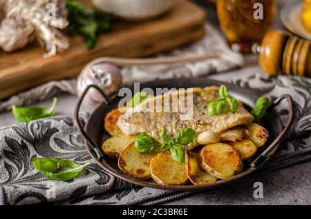 Delizioso pesce con patate arrosto e bio aglio Foto Stock