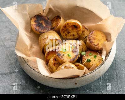 Bambino arrosto patate e microgreen nella piastra di artigianato su sfondo grigio. Baby semi di patate arrosto. Foto Stock