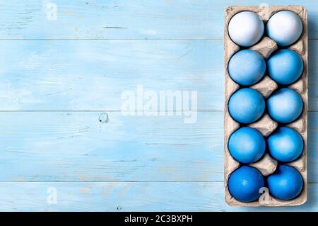 Concetto di Pasqua. Uova Ombre in blu in cartone su sfondo di legno blu con spazio per la copia del testo. Vista dall'alto o in piano. Classico Foto Stock