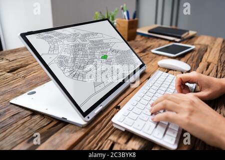 Close-up di un imprenditore analizzando il catasto mappa sul computer in ufficio Foto Stock