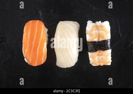 Set di sushi nigiri, colpo di testa di primo piano su uno sfondo nero. Salmone fresco, pesce bianco e gamberetti sul riso Foto Stock