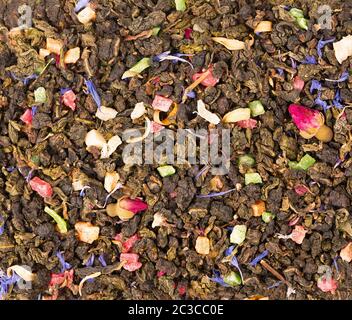 Tè Guan Yin cravatta con boccioli di rosa, frutta candita, petali di fiori di mais. Tè biologico di fondo. Vista dall'alto. Primo piano. Foto Stock