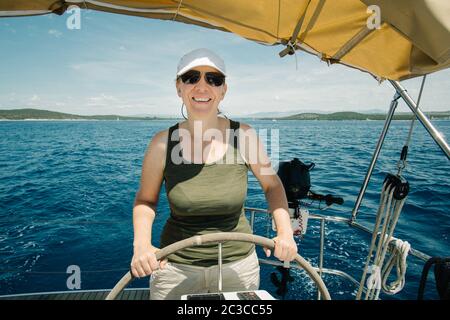 Skipper femmina sul volante di uno yacht. Concetto di vela e nautica da diporto. Foto Stock