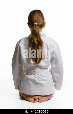 Ragazza in classe judo, seduta sul pavimento, vista posteriore Foto Stock