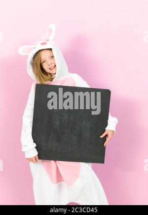 bella ragazza bionda con intimo costume di coniglio e lavagna si posa in studio ed è felice Foto Stock