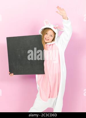 bella ragazza bionda con intimo costume di coniglio e lavagna si posa in studio ed è felice Foto Stock