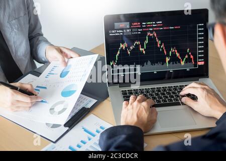 Imprenditori parlando di mercato azionario investire trading online analisi discutendo grafico finanziario a fini di investimento in discussione gli operatori office Foto Stock