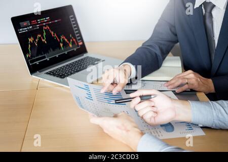 Imprenditori parlando di mercato azionario investire trading online analisi discutendo grafico finanziario a fini di investimento in discussione gli operatori office Foto Stock