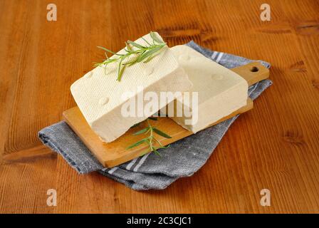 Due blocchi di cagliata di fagioli freschi (tofu) sul tagliere Foto Stock