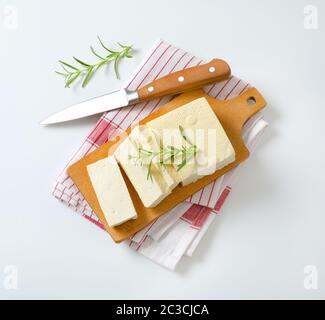 Blocco a fette di cagliata di fagioli freschi (tofu) su tagliere Foto Stock