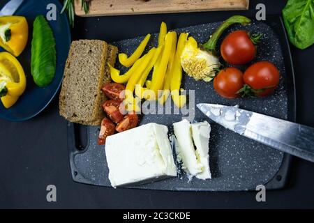 Costolette sotto salsa al miele su una tavola di legno accanto ai pomodori, peperoni e basilico con rosmarino, feta affettata con cracker. Viste dall'alto Foto Stock