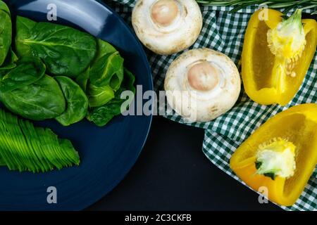 Pepe bulgaro, funghi e avocado affettato su un piatto blu, oltre alla composizione del tovagliolo nella gabbia verde bianca. Viste dall'alto Foto Stock