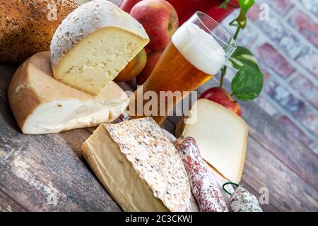 Formaggi e Tomme de Savoie con un bicchiere di birra, formaggio francese Savoia, sulle alpi francesi Francia. Foto Stock