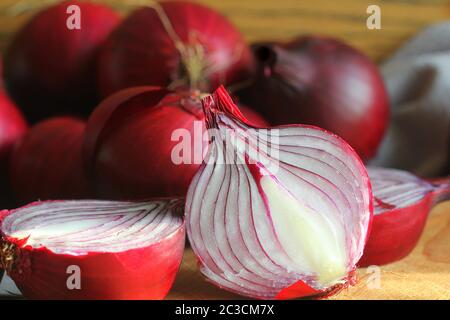 Cipolle rosse su tagliere di legno su sfondo di legno scuro a struttura rustica. Vista dall'alto, spazio per il testo . Foto Stock