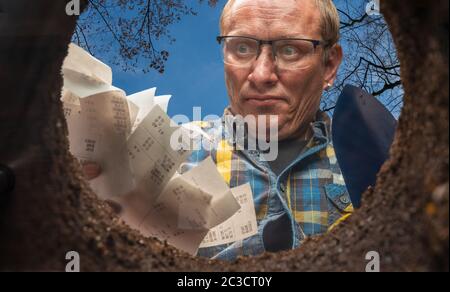 un uomo vuole sbarazzarsi delle sue ricevute in un buco nel terreno Foto Stock