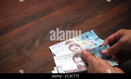 L'uomo considera i nuovi soldi di carta ucraini. Per la prima volta vede nuove note in valore nominale di 1000 hryvnia. Mettere a fuoco le mani in primo piano. Spazio di testo Foto Stock