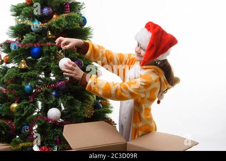 La ragazza tira fuori dalla scatola sfera dell'albero di Natale e pende sull'albero di Natale Foto Stock