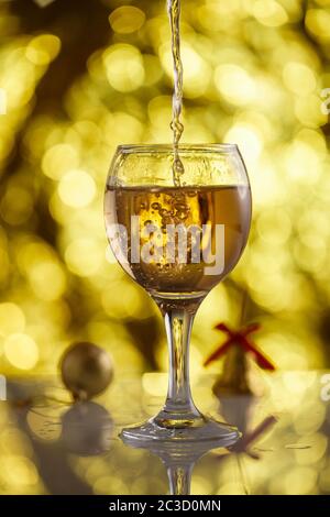 Vetro di champagne su fondo oro con un bellissimo bokeh e giocattoli di Natale Foto Stock