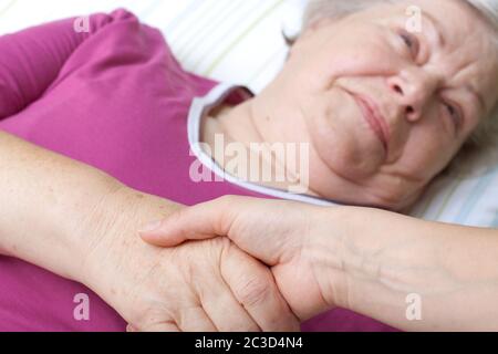 La donna anziana si trova nel letto e saluta l'infermiera Foto Stock