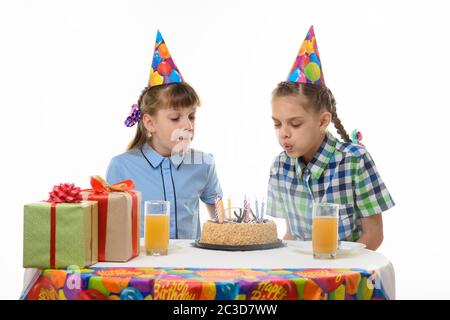 I bambini soffiano le candele su una torta di compleanno Foto Stock