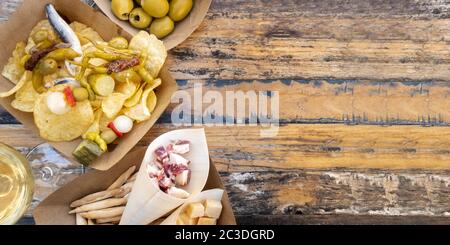 Tapas, pinchos e vino, foto panoramica a soffitto su un tavolo di legno. Formaggio, jamon e olive, gildas con peperoni e patate ch Foto Stock