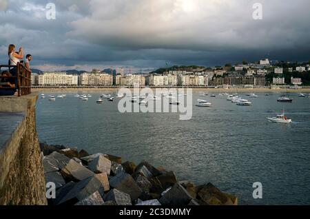 La gente scatta foto alla baia di la Concha con il paesaggio urbano di San Sebastian prima di una tempesta dal porto di San Sebastian. Gipuzkoa. Paesi baschi.Spagna Foto Stock