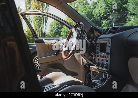 Ampio interno di un antico hatchback italiano. Volante in legno in una giornata di sole, le porte si aprirono lasciando in luce e calore. Tenuto pulito da un'auto enthusi Foto Stock