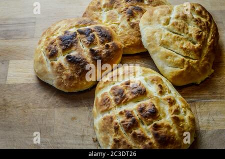 Piccoli pani di focaccia italiana fatti in casa e cucinati di fresco su un tavolo di legno da vicino. La focaccia è un tradizionale pane piatto italiano cotto al forno. Foto Stock