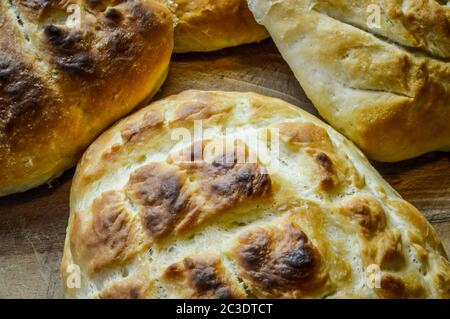 Piccoli pani di focaccia italiana fatti in casa e cucinati di fresco su un tavolo di legno da vicino. La focaccia è un tradizionale pane piatto italiano cotto al forno. Foto Stock