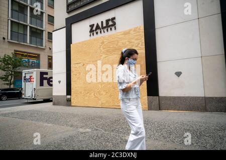 Una donna mascherata distratta dal suo smartphone passa davanti a un negozio di gioielleria Zales sulla Fifth Avenue a New York giovedì 11 giugno 2020. Signet Jewellers, il proprietario dei marchi di gioielli Zales, Kay, Piercing Pagoda e Jared ha riferito che chiuderà 380 negozi negli Stati Uniti e in Europa. (© Richard B. Levine) Foto Stock