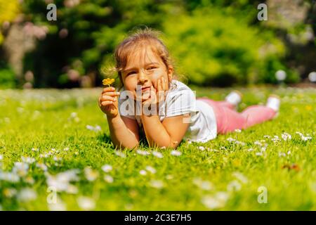 Ragazza giovane che tiene il fiore giallo Buttercup sul prato Foto Stock