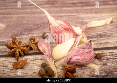 Spicchi d'aglio, anice stellato, spezie su un tavolo di legno. Primo piano Foto Stock