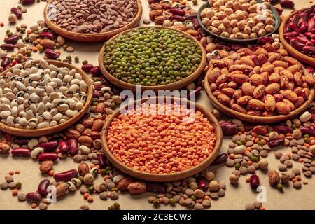 Assortimento di legumi su sfondo marrone. Lenticchie, soia, ceci, fagioli rossi, una ventata di impulsi Foto Stock