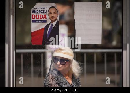 Varsavia, Polonia. 19 giugno 2020. Una donna che indossa uno scudo facciale è vista sotto un poster del presidente polacco in carica Andrzej Duda ad una fermata dell'autobus a Varsavia, Polonia, il 19 giugno 2020. La Polonia terrà le sue elezioni presidenziali il 28 giugno, con un turno di run-off due settimane dopo. Le elezioni, originariamente previste per il maggio 10, non si sono svolte a causa della pandemia della COVID-19 e del conseguente blocco. Credit: Jap Arriens/Xinhua/Alamy Live News Foto Stock