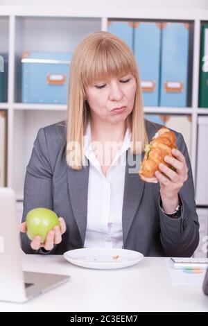 Donna in ufficio che mangia cibo durante la sua pausa. Concetto di business, dieta e stile di vita sano. Foto Stock